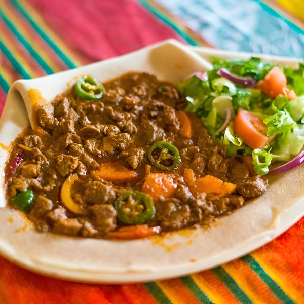 Queen Sheba Ethiopian Cuisine's Kitfo, a minced meat dish, with injera bread and a side salad.