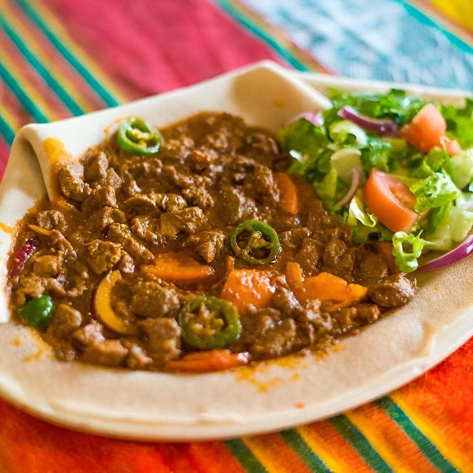 Queen Sheba Ethiopian Cuisine's Kitfo, a minced meat dish, with injera bread and a side salad.