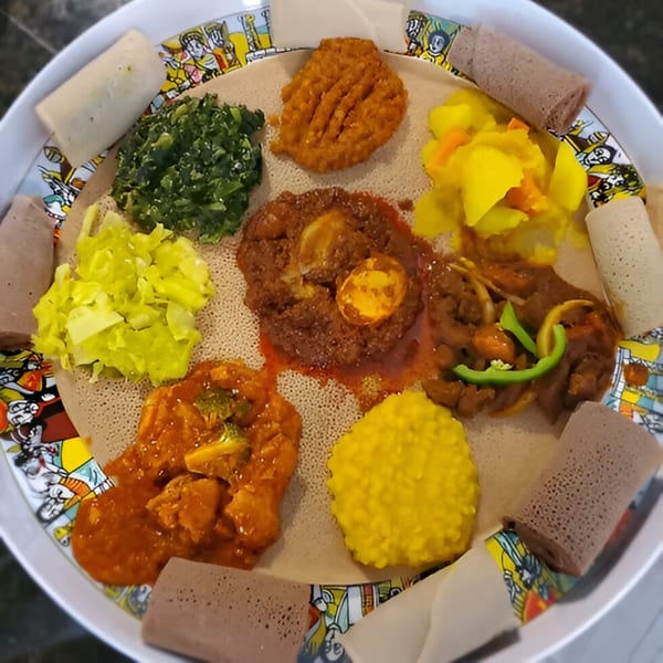 A colorful platter of Ethiopian cuisine, including injera bread, stews, and vegetables, from Queen Sheba.